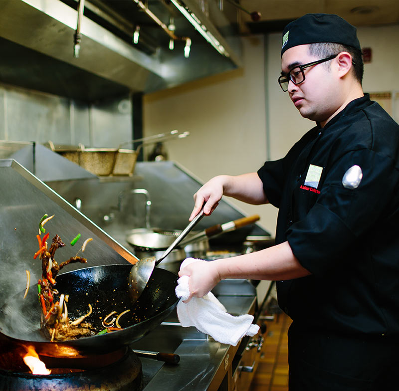 Asian culinary student cooking with a wok.