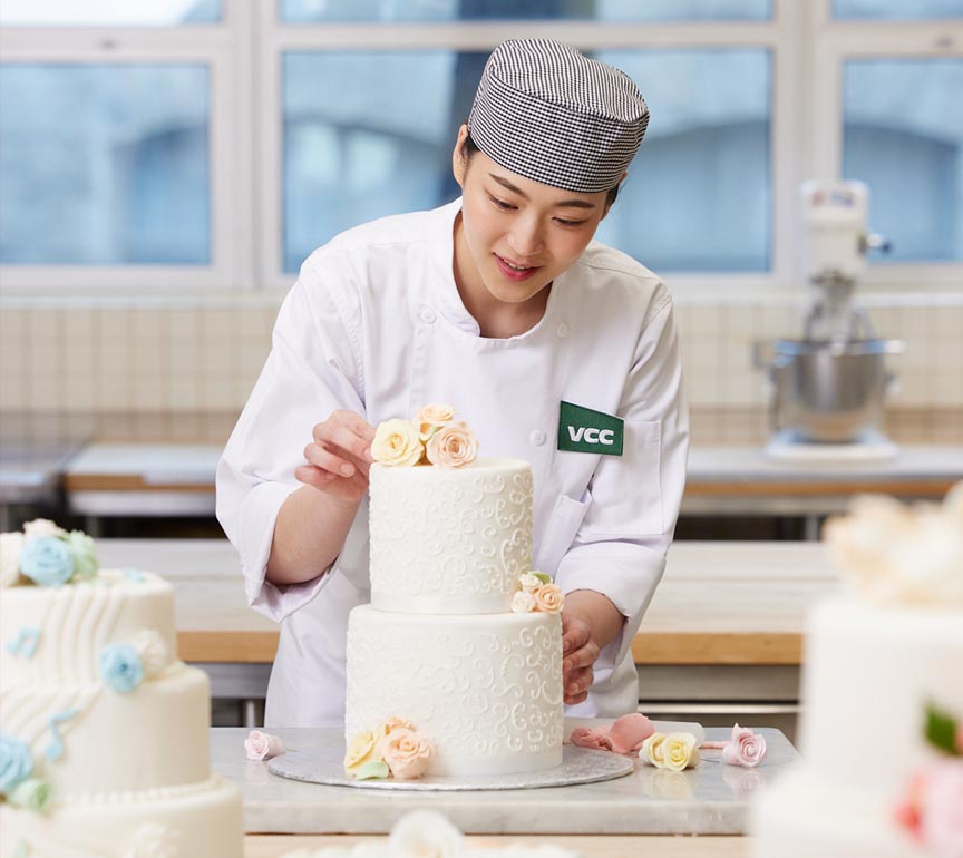Baking student decorating a wedding cake