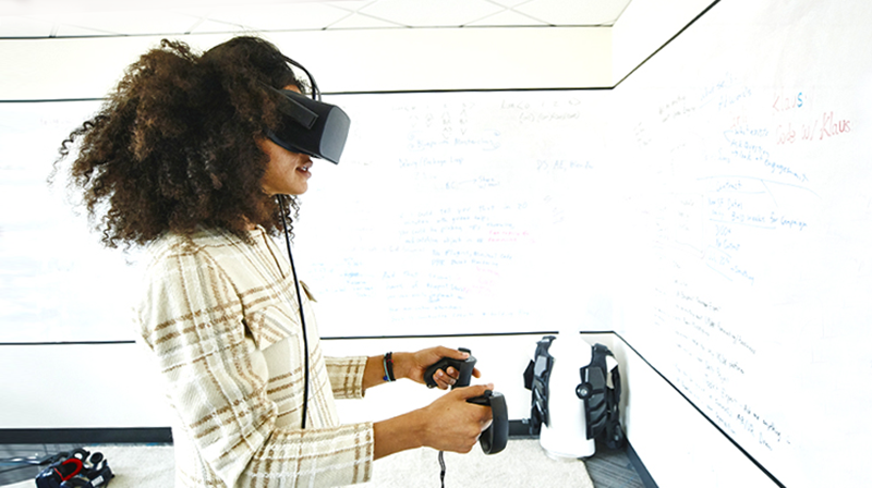 Woman using VR headset and handsets in classroom with whiteboards