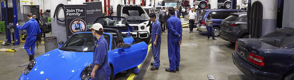 Automotive repair shop with mechanics working on various cars.