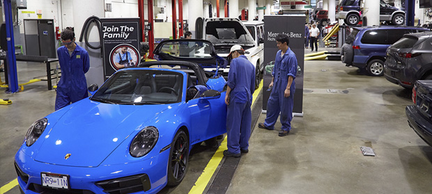 Automotive repair shop with mechanics working on various cars.