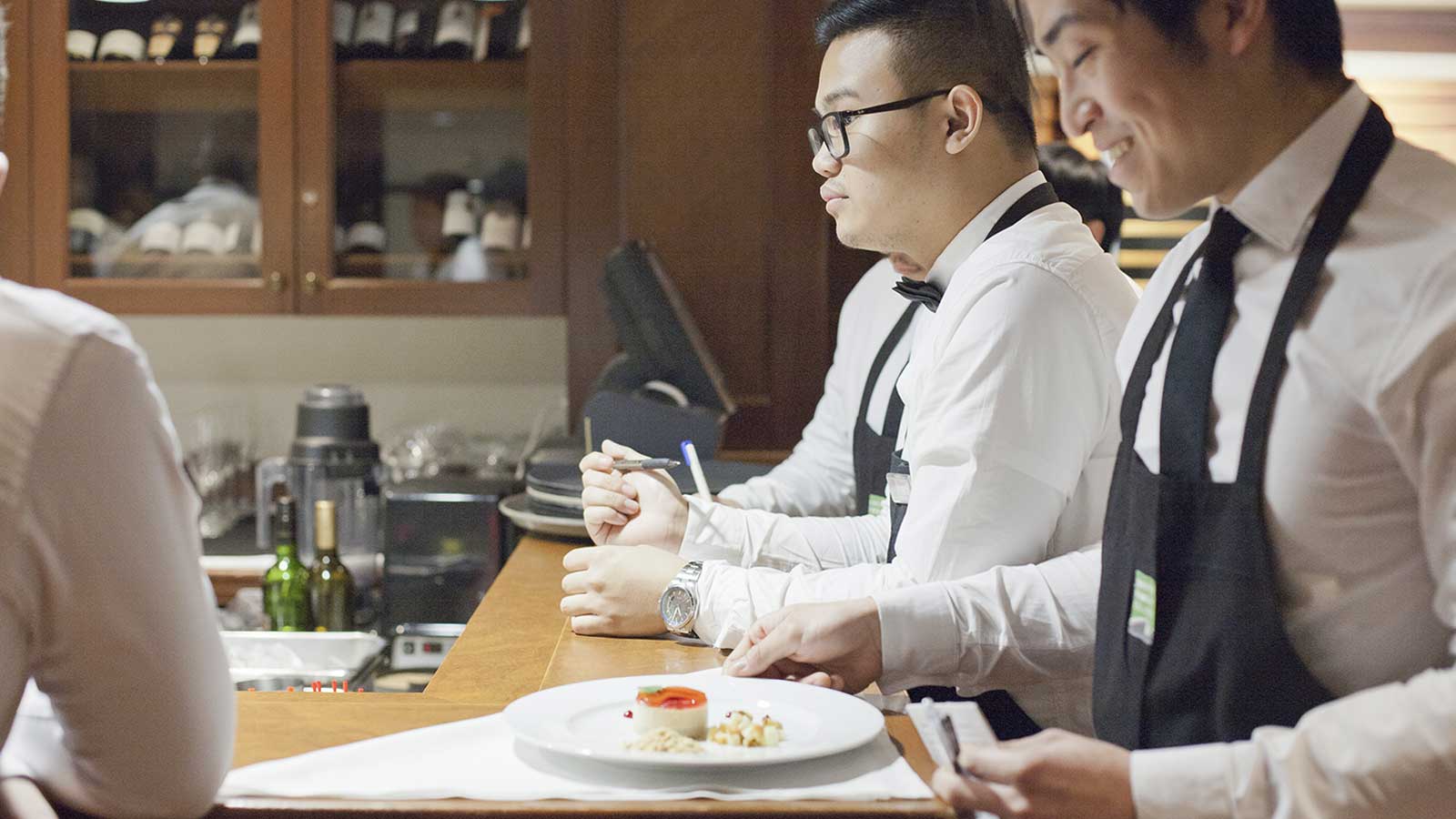 Hospitality students inpecting a plate of food before serving it to a customer