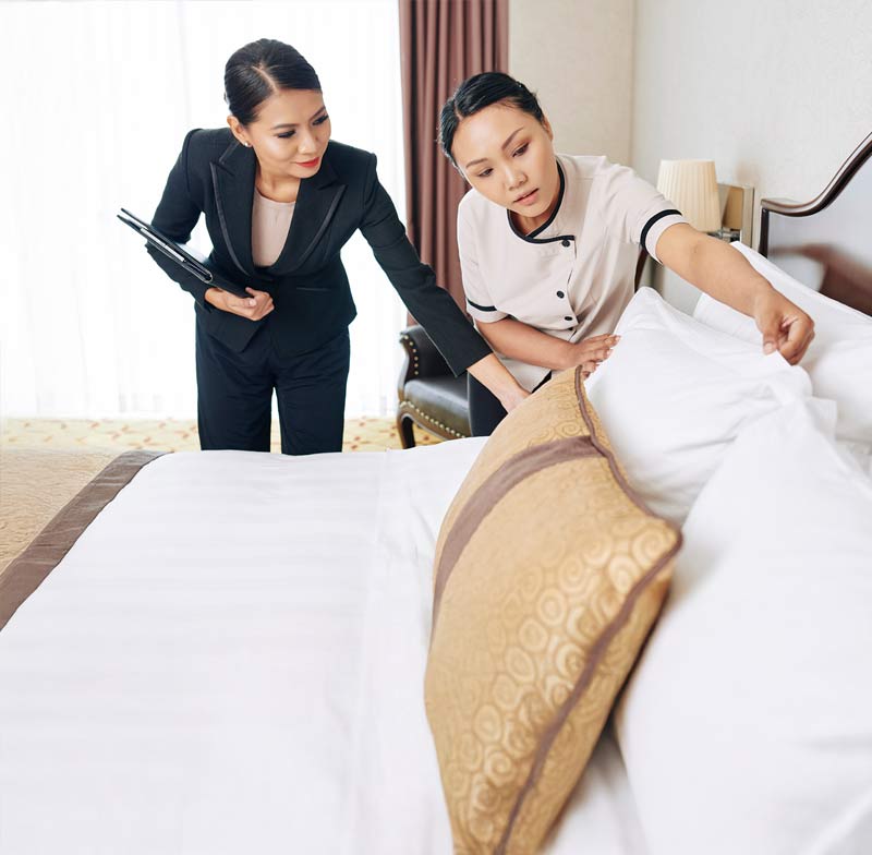 Hospitality student being taught how to correctly set up the pillow on the hotel bed